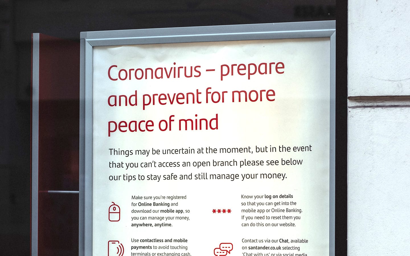 Poster reads "Coronavirus, prepare and prevent for more peace of mind." Sign outside bank giving Coronavirus information about online banking alternatives.