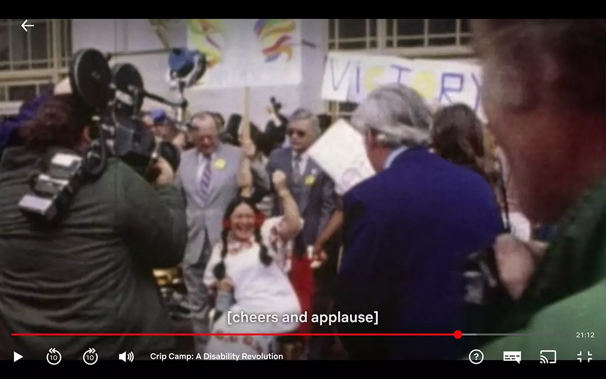 Closed captions "cheers and applause" provide extra context to onscreen audio.