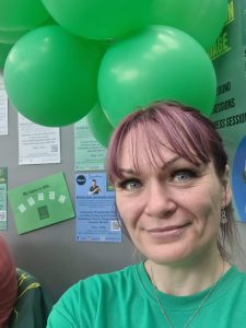 Julia in a green t-shirt, surrounded by green balloons.